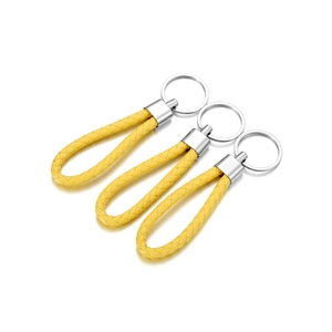 Detailed view of three bright yellow braided leather keychains with silver metal rings