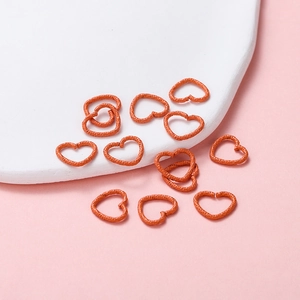 Detail of orange heart-shaped open jump rings with textured finish for DIY jewelry