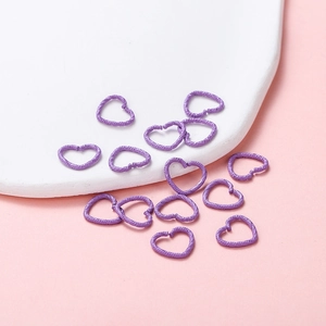 Macro detail of heart-shaped jump rings with grainy purple texture for DIY jewelry making