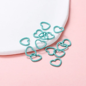 Detailed macro view of heart-shaped jump rings with teal paint and hammered texture