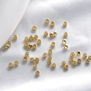 Macro shot of gold cylindrical beads for DIY jewelry making on white silk fabric