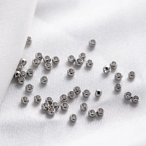 Silver crimp beads for DIY jewelry making on white fabric background, macro view