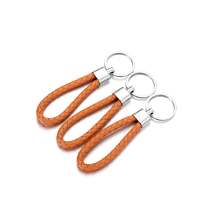 Three orange woven leather keychains with polished silver rings on a white background