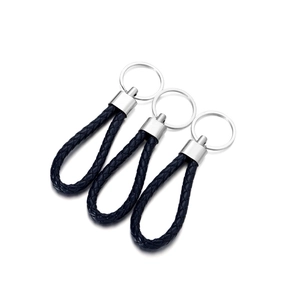 Macro detail of three handmade black braided leather keychains with polished metal rings