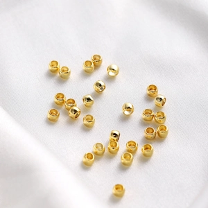 Macro detail of 18K gold plated crimp beads on white silk for DIY jewelry making