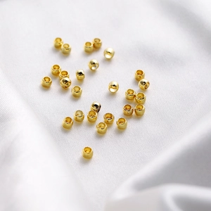 Macro shot of 18K gold plated jewelry beads on white silk for DIY bracelet making