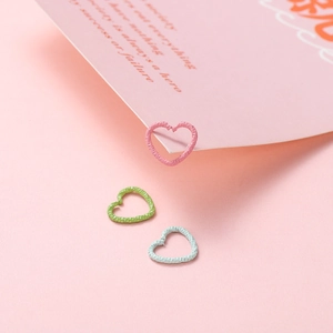 Macro shot of heart-shaped jump rings with hammered texture in pastel pink, green and blue