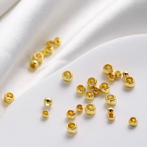 Macro view of 18K gold-plated spacer beads on white silk for DIY jewelry making