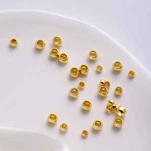 Macro shot of assorted size 18K gold plated jewelry spacer beads on white surface