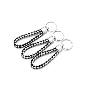 Detailed view of three braided black and white leather keychains with silver metal rings