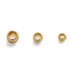 Detailed macro view of three sizes of 18K gold plated copper crimp beads for DIY jewelry