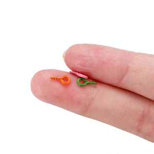 Vista macro de mini tornillos de ojo de 4x8mm para bisutería DIY sujetos con dedos