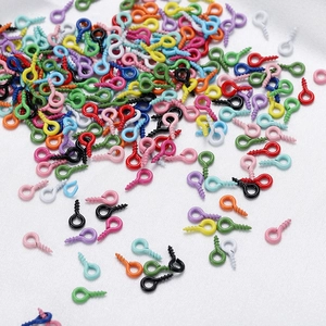 Primer plano de tornillos de ojo de 4x8mm de colores para joyería sobre seda