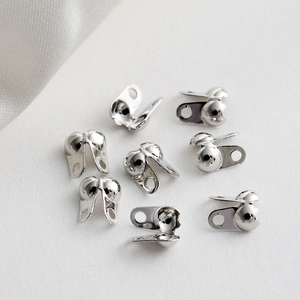 Close-up of silver-plated ball chain end clasps and fold-over crimp covers for jewelry making