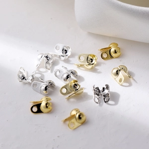 Macro view of gold and silver bead tips for jewelry making on white fabric
