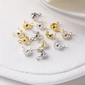 Close-up of gold and silver bead tips for DIY jewelry making on white stone texture