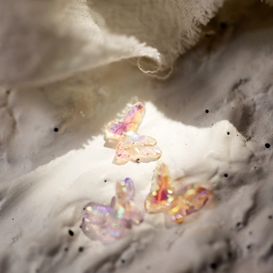 Macro detail of iridescent mini resin butterflies with aurora glitter for DIY nail art