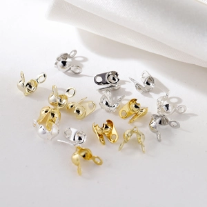 Macro shot of 18K gold and silver bead tips for jewelry making on white silk