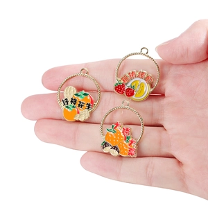 Close-up of enamel fruit charms with lucky symbols like persimmon and peanut details