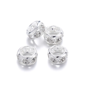 Détail macro de quatre perles d'espacement argentées avec strass pour création de bijoux