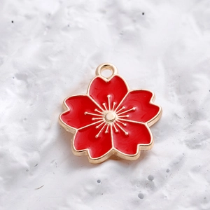 Macro-opname van rode emaille kersenbloesem hanger met goudmetaal voor DIY-sieraden