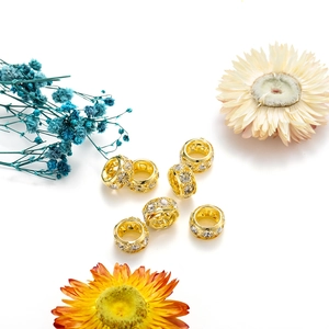 Détail de perles d'espacement dorées avec cristaux blancs et motifs sculptés ajourés