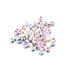 Close-up of white acrylic round beads with colorful letter H for DIY jewelry making