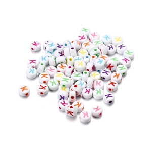 Macro detail of white acrylic letter K beads with colorful printing for DIY jewelry making