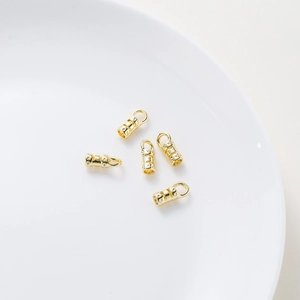 Close-up of five 18K gold-plated jewelry clasps with engraved patterns on white ceramic