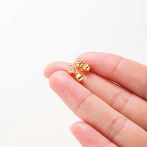 Macro di ciondoli a forma di pallottoliere placcati oro 18K con smalto bianco sul dito