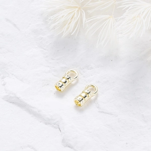 Detailed view of 18K gold-plated jewelry connectors with engraved cross textures on stone