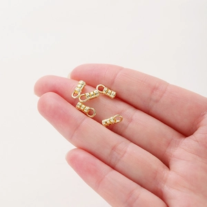 Five 18K gold-plated jewelry connector clasps held on fingertips for DIY necklace making