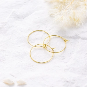 Detalle de aros y ganchos de pendientes bañados en oro 18K en fondo de piedra