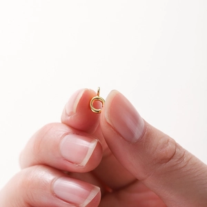 Macro view of a tiny 18K gold-plated spring clasp connector held by fingers