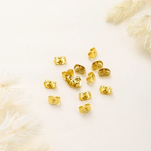 Macro shot of 18K gold-plated butterfly earring backs with polished metallic finish