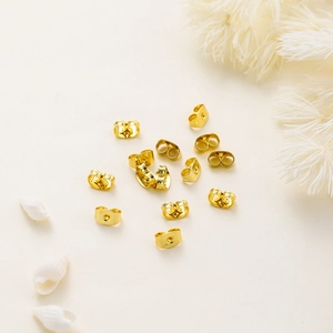 Macro shot of shiny 18K gold plated copper butterfly earring backs on a white background