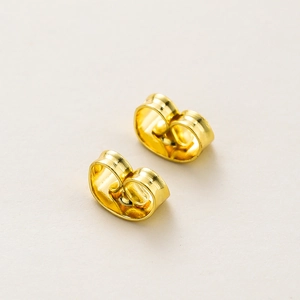Macro shot of 18K gold-plated copper butterfly earring backs with polished metallic finish