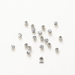 Detailed close-up of 3mm silver textured metal beads with spiral engraved patterns