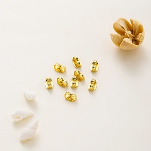 Polished 14k gold plated butterfly earring backs set on minimalist beige background