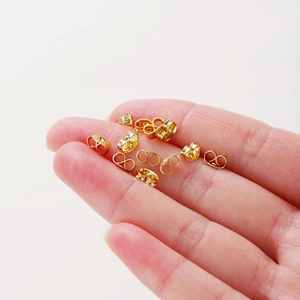 Golden 14k copper butterfly earring backs shown on fingertips for size comparison