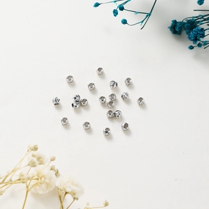 Detailed view of silver-plated copper spacer beads with textured flower engraving
