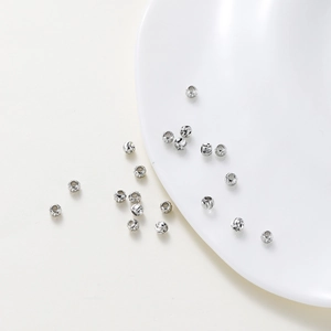 Detailed view of silver-plated copper beads with spiral flower patterns for DIY jewelry making