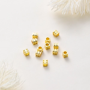 Foto macro de cuentas espaciadoras cúbicas bañadas en oro de 18K para bisutería artesanal