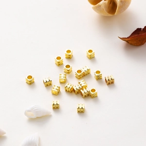 Detalle macro de cuentas cuadradas bañadas en oro de 18K para creación de joyería DIY