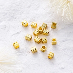 Vista macro de cuentas espaciadoras cuadradas bañadas en oro de 14K para joyería DIY