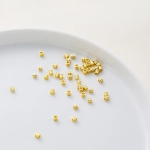 Detalle macro de cuentas espaciadoras de cubo de 4mm en oro de 18K con ranuras para joyería