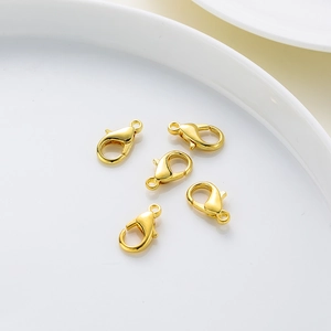Five shiny gold-plated lobster clasps on a white ceramic tray for jewelry making