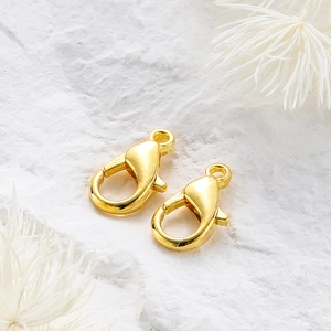 Macro shot of two polished 14k gold-plated lobster clasps for jewelry making