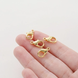 Close-up of 14k gold-plated lobster clasps for DIY jewelry making on fingertips