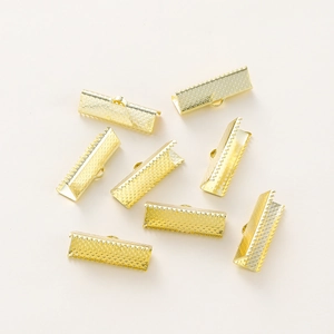 Detail of gold-plated ribbon end crimps with serrated teeth and textured diamond pattern